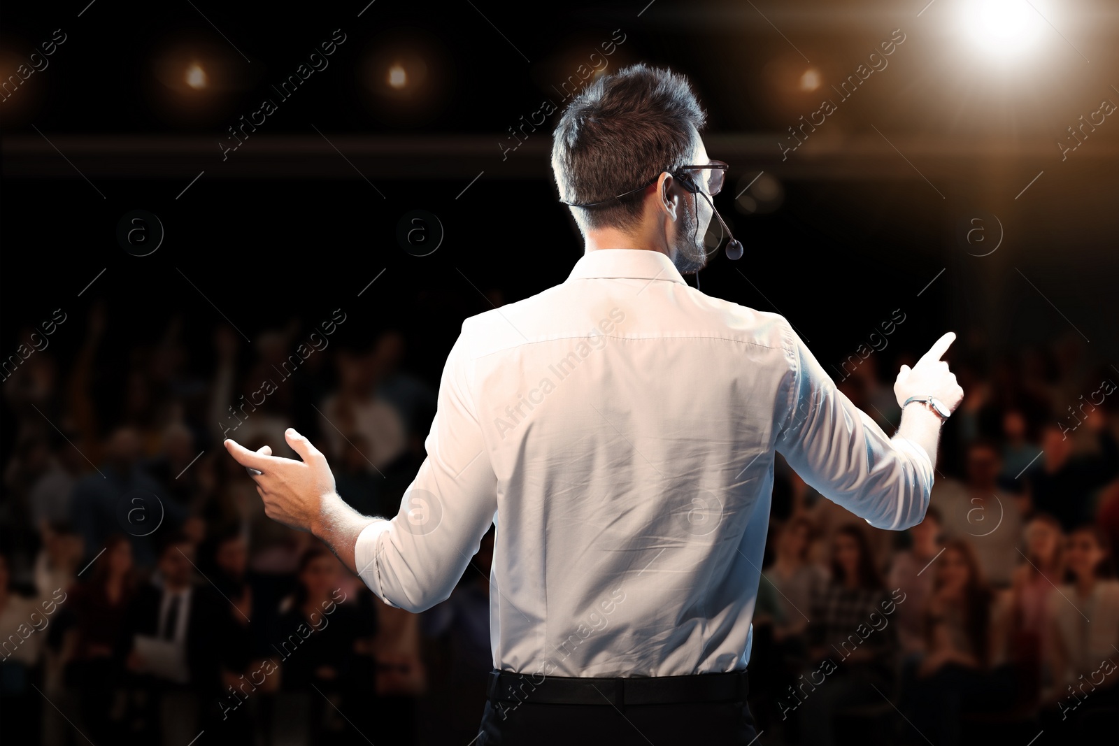 Image of Motivational speaker with headset performing on stage, back view