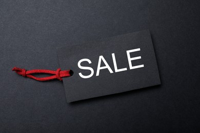 Photo of Tag with word Sale on dark background, top view. Black Friday