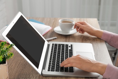 Photo of Woman using laptop at table, closeup. Space for design