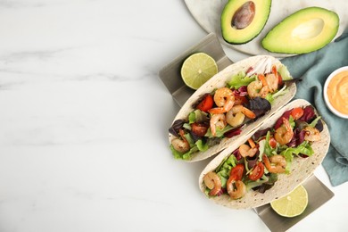 Photo of Delicious tacos with shrimps, lime and avocado on white table, flat lay. Space for text
