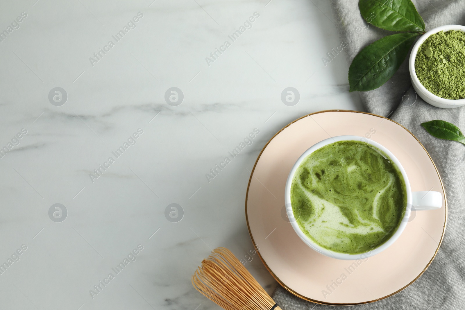 Photo of Cup of fresh matcha latte, powder and bamboo whisk on white marble table, flat lay. Space for text