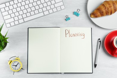 Notebook with word Planning, coffee, alarm clock, computer keyboard, croissant and stationery on white table, flat lay