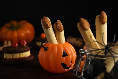 Photo of Delicious desserts decorated as monster fingers on wooden table. Halloween treat