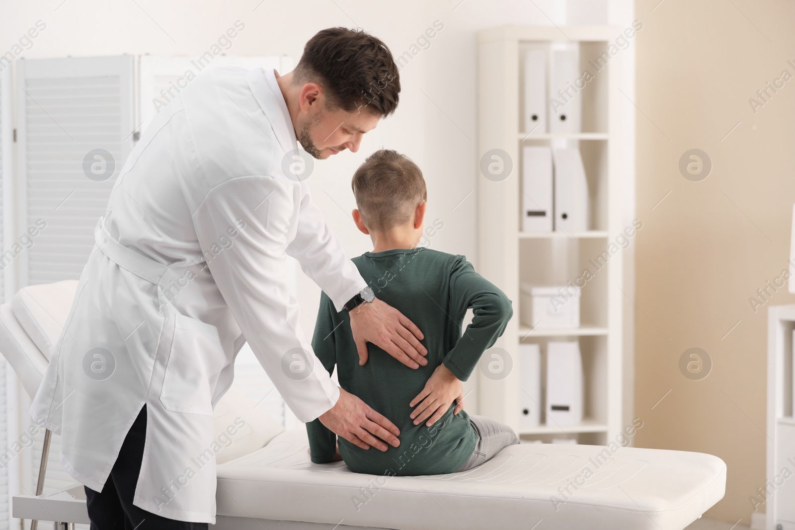 Photo of Chiropractor examining child with back pain in clinic