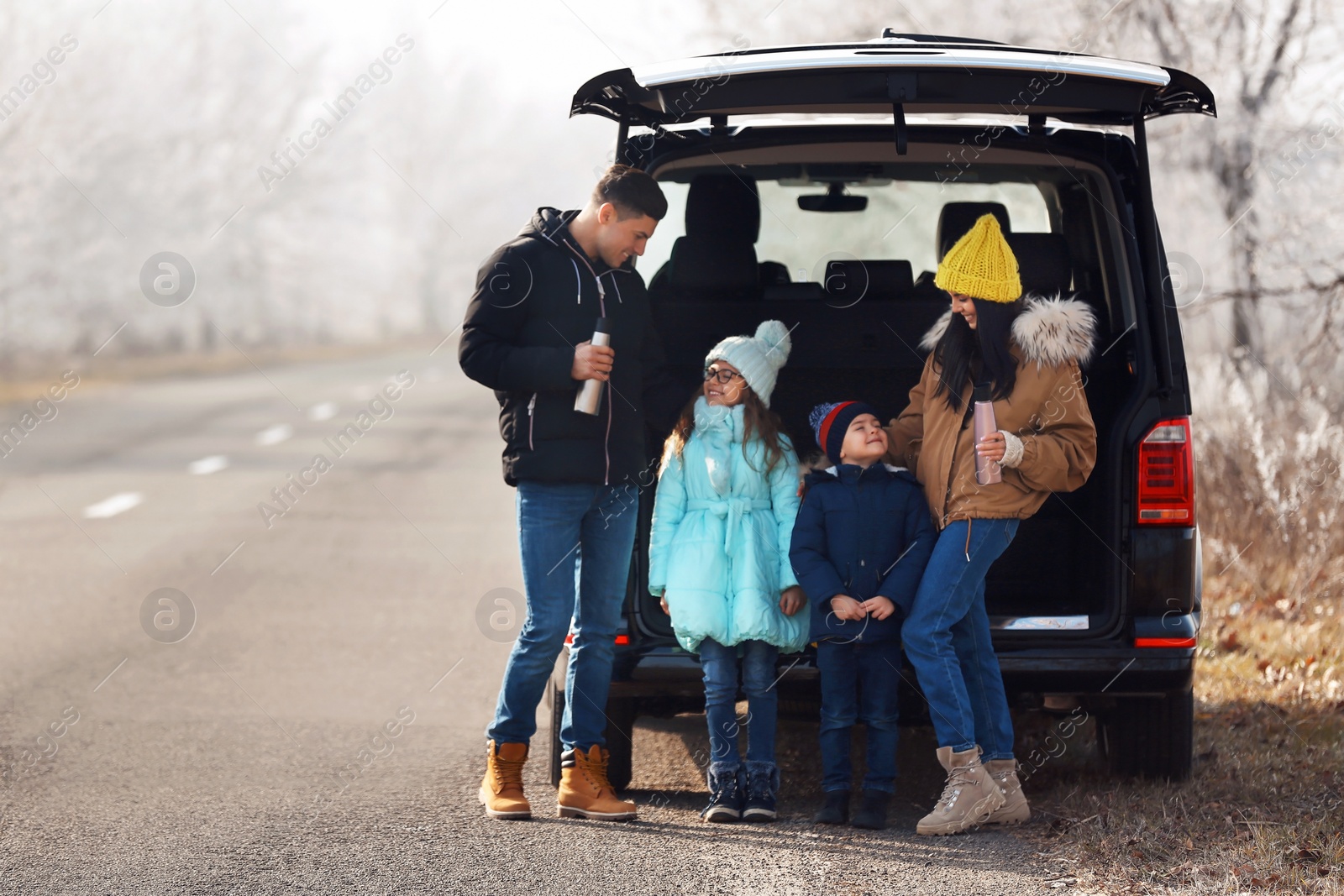 Photo of Happy family with little children near modern car on road