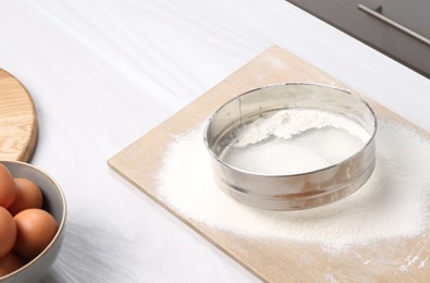 Sieve with flour, eggs and rolling pin on table in kitchen