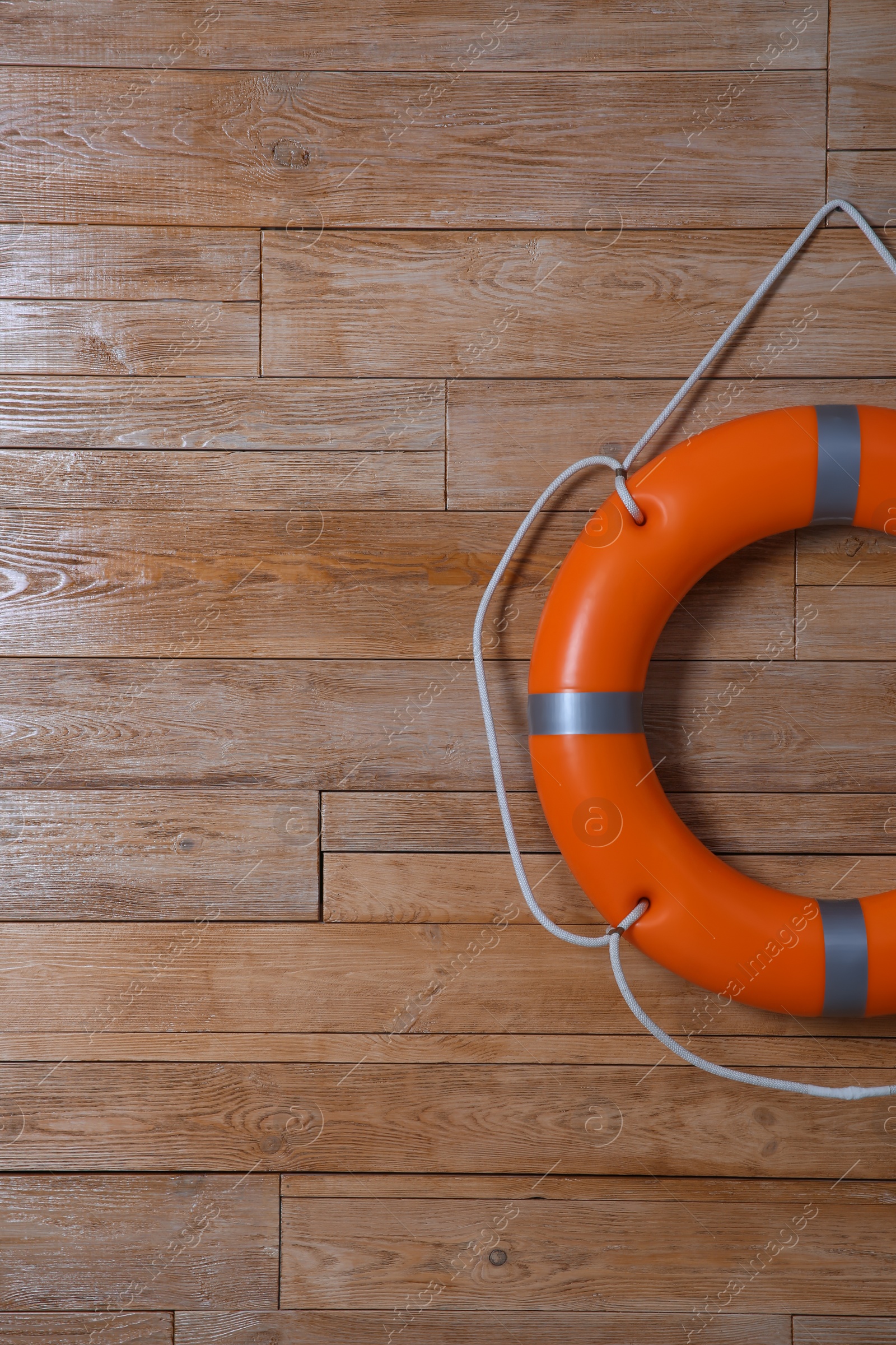 Photo of Orange lifebuoy on wooden background, space for text. Rescue equipment