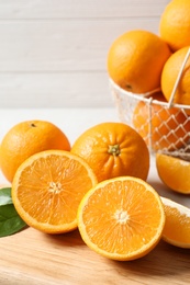 Photo of Wooden board with ripe oranges on table