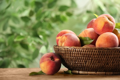 Photo of Fresh sweet peaches in wicker basket on wooden table outdoors