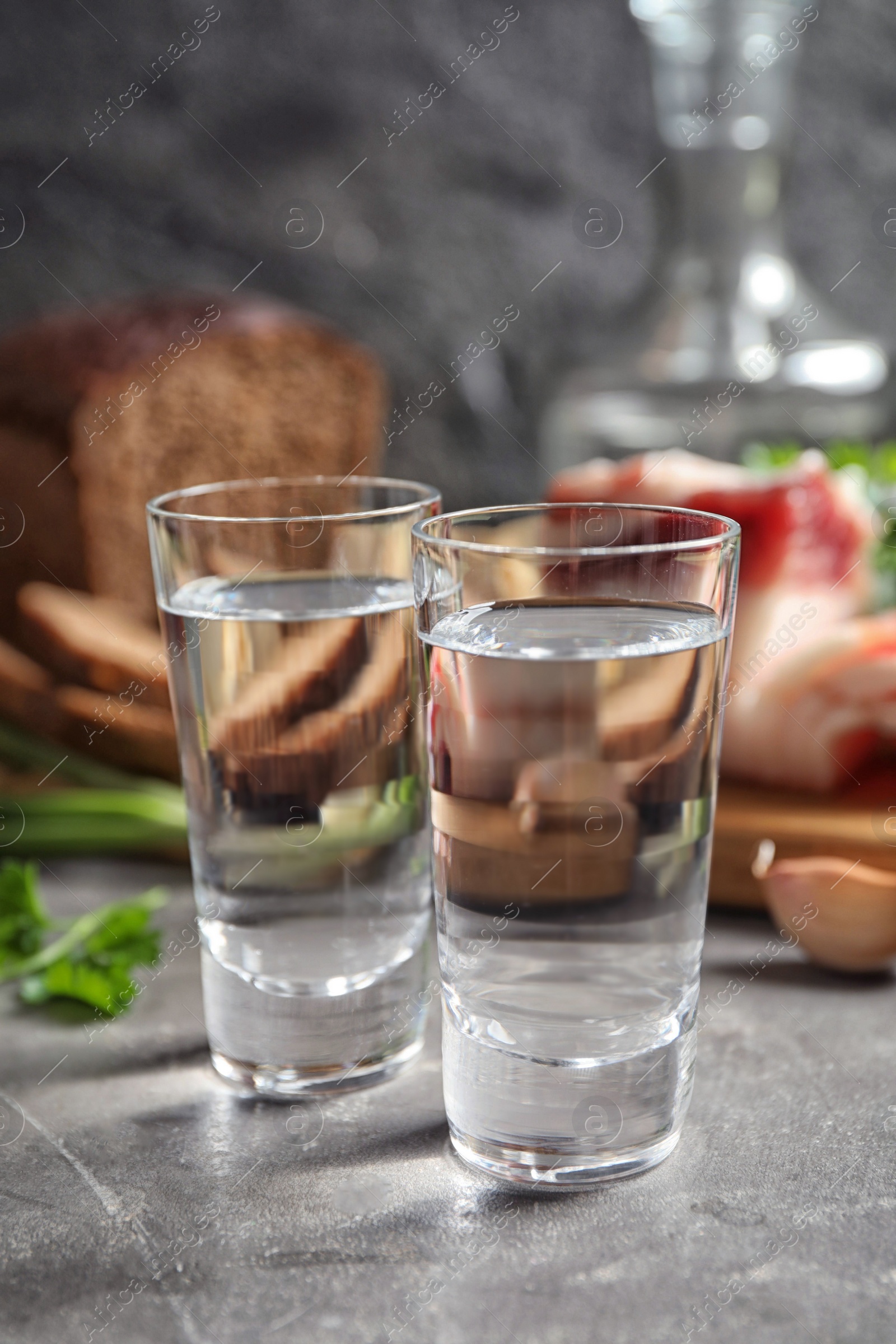 Photo of Cold Russian vodka with snacks on grey table, closeup