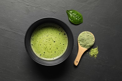 Cup of fresh matcha tea and bamboo spoon with green powder on black table, flat lay