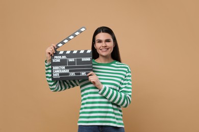 Photo of Happy actress with clapperboard on beige background. Film industry
