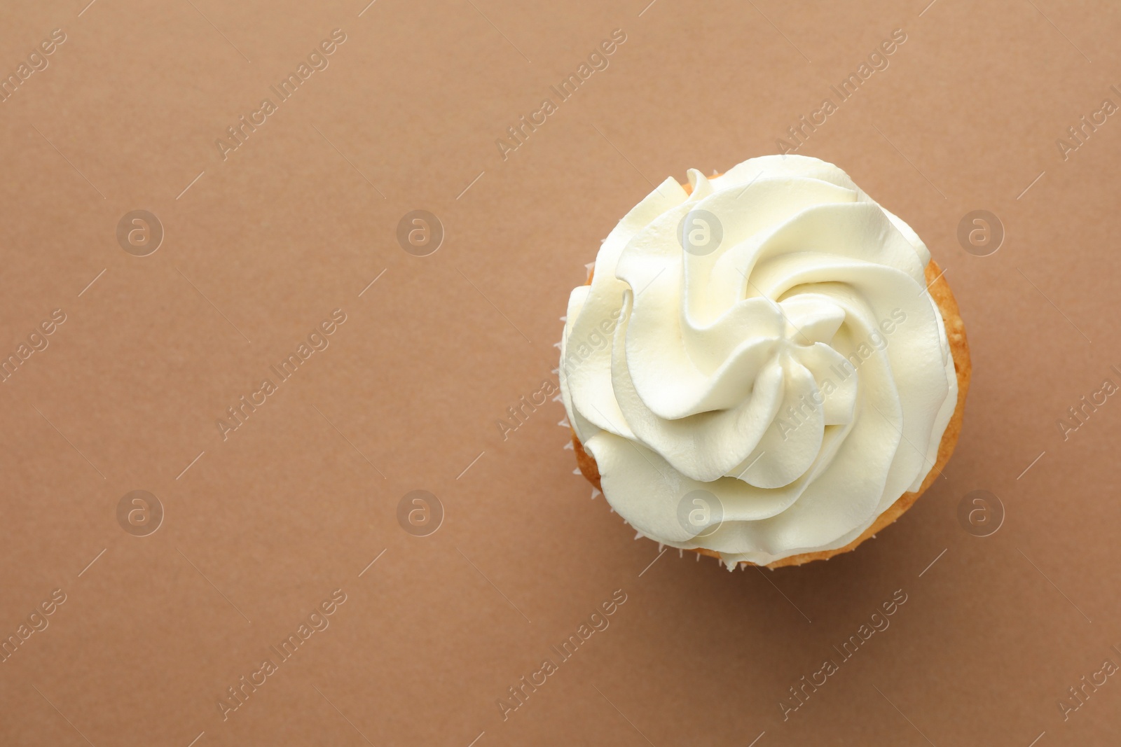 Photo of Tasty vanilla cupcake with cream on dark beige background, top view. Space for text