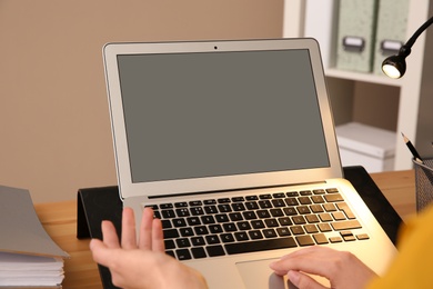 Young woman using modern laptop at table, closeup