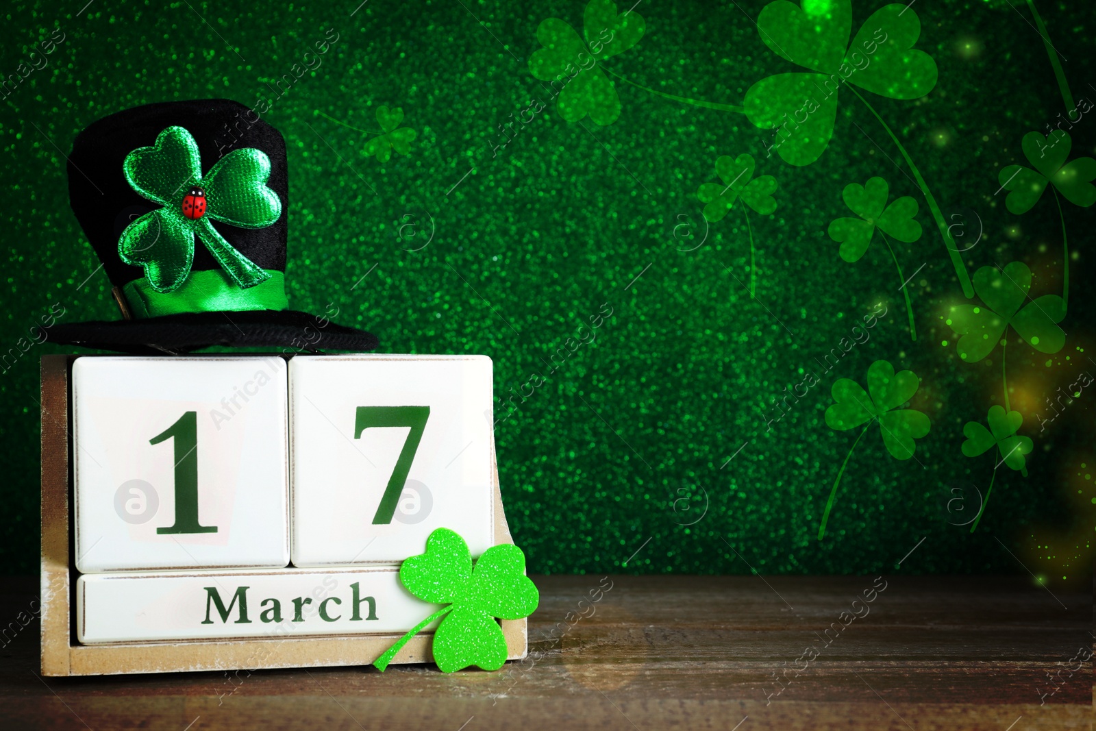 Image of Black leprechaun hat, clover leaf and wooden block calendar on table, space for text. St. Patrick's Day celebration