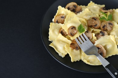 Photo of Delicious ravioli with mushrooms and fork on black table, closeup. Space for text
