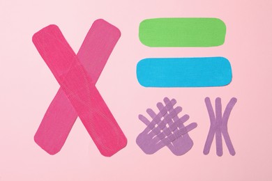 Photo of Different kinesio tape pieces on light pink background, flat lay
