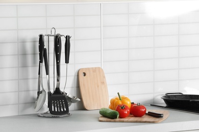 Photo of Clean cookware, vegetables and utensils on table in kitchen