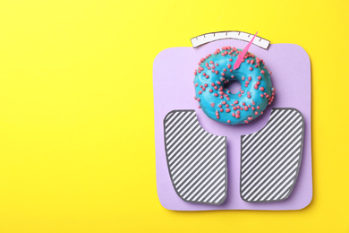 Photo of Scales made with donut on yellow background, top view. Space for text