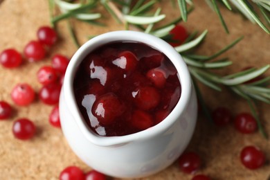 Photo of Cranberry sauce in pitcher, fresh berries and rosemary on board, above view
