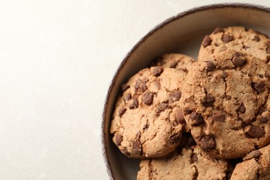 Photo of Delicious chocolate chip cookies in bowl on light table, top view. Space for text