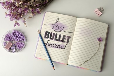 Image of Improve your productivity. Notebook with words My bullet journal, stationery and flowers on white table, flat lay