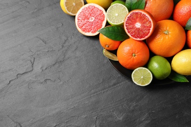 Photo of Different citrus fruits on black table, above view. Space for text