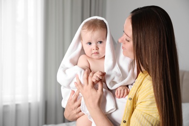 Photo of Mother holding cute little baby wrapped with towel indoors after bath
