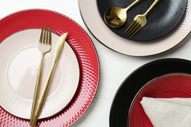 Stylish ceramic plates, cutlery and napkin on white wooden table, flat lay