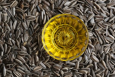 Photo of Sunflower oil in glass bowl on seeds, top view