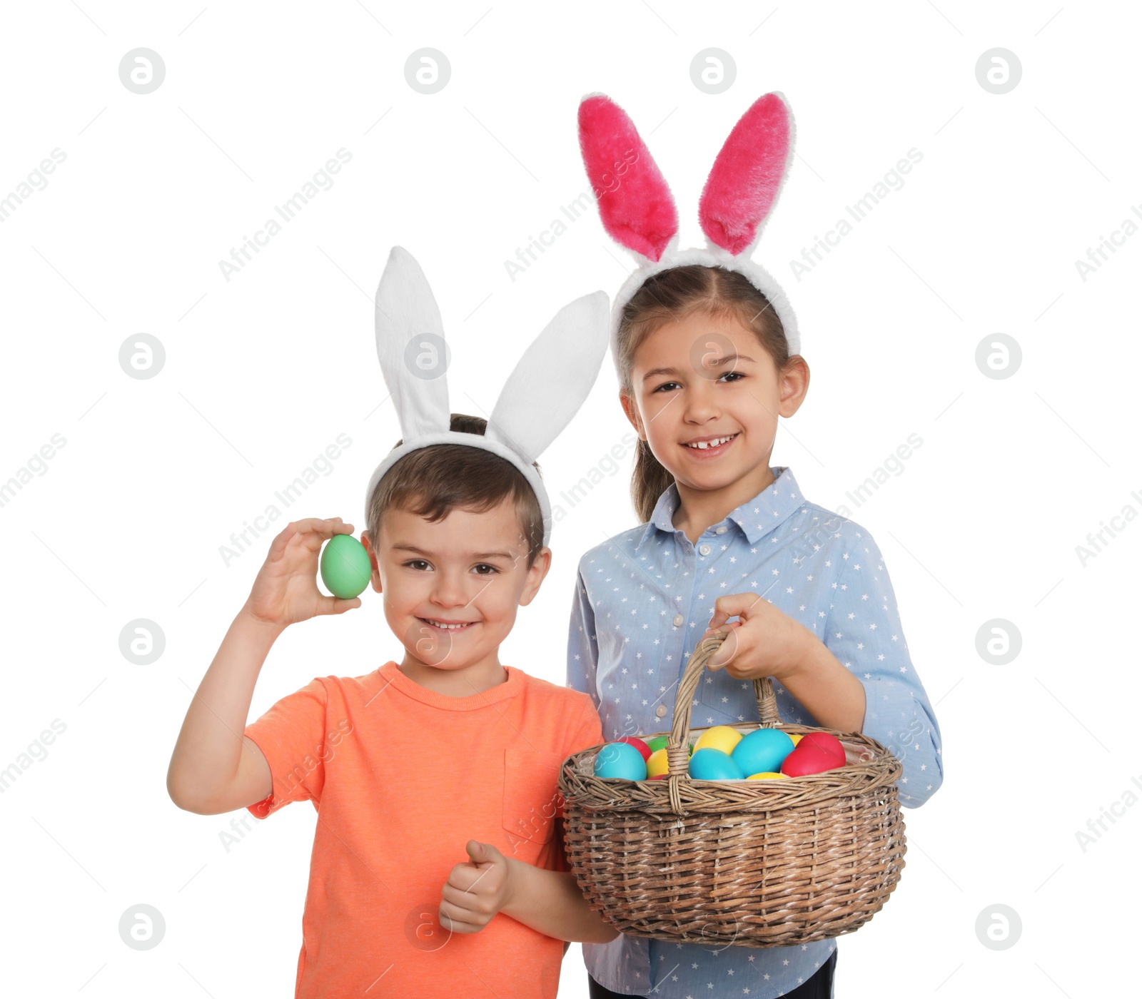 Photo of Cute children in bunny ears headbands holding basket with Easter eggs on white background