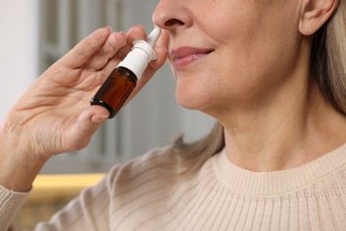Photo of Medical drops. Woman using nasal spray indoors, closeup