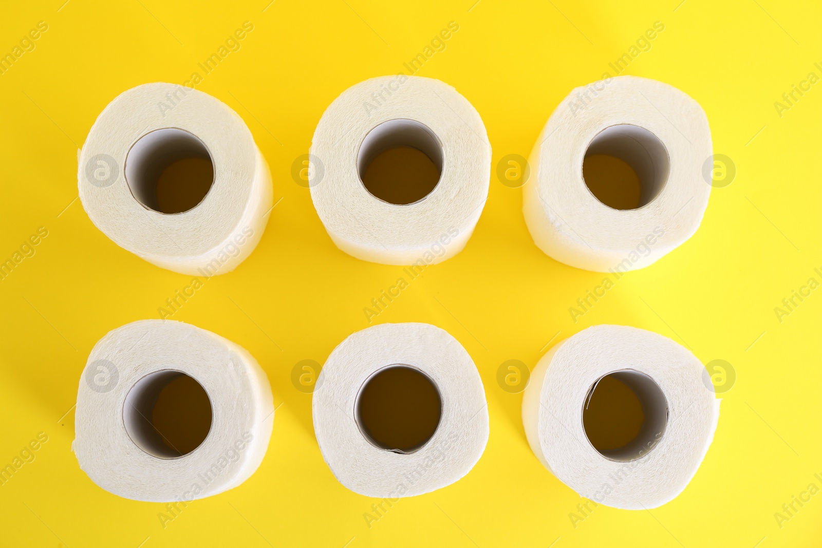 Photo of Many soft toilet paper rolls on yellow background, flat lay