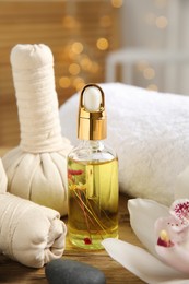 Beautiful spa composition with essential oil and orchid flower on wooden table against blurred lights, closeup