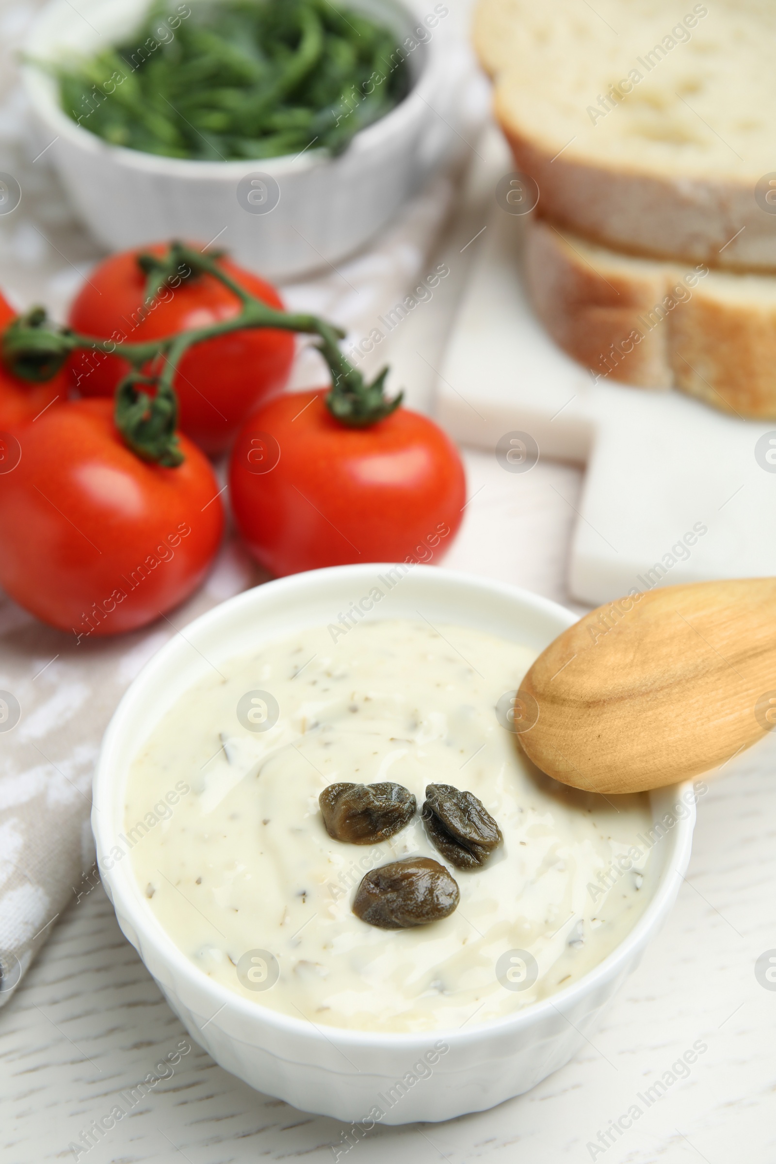 Photo of Creamy caper sauce in bowl on white table, closeup