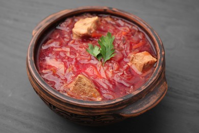 Tasty borscht in bowl on grey wooden table, closeup