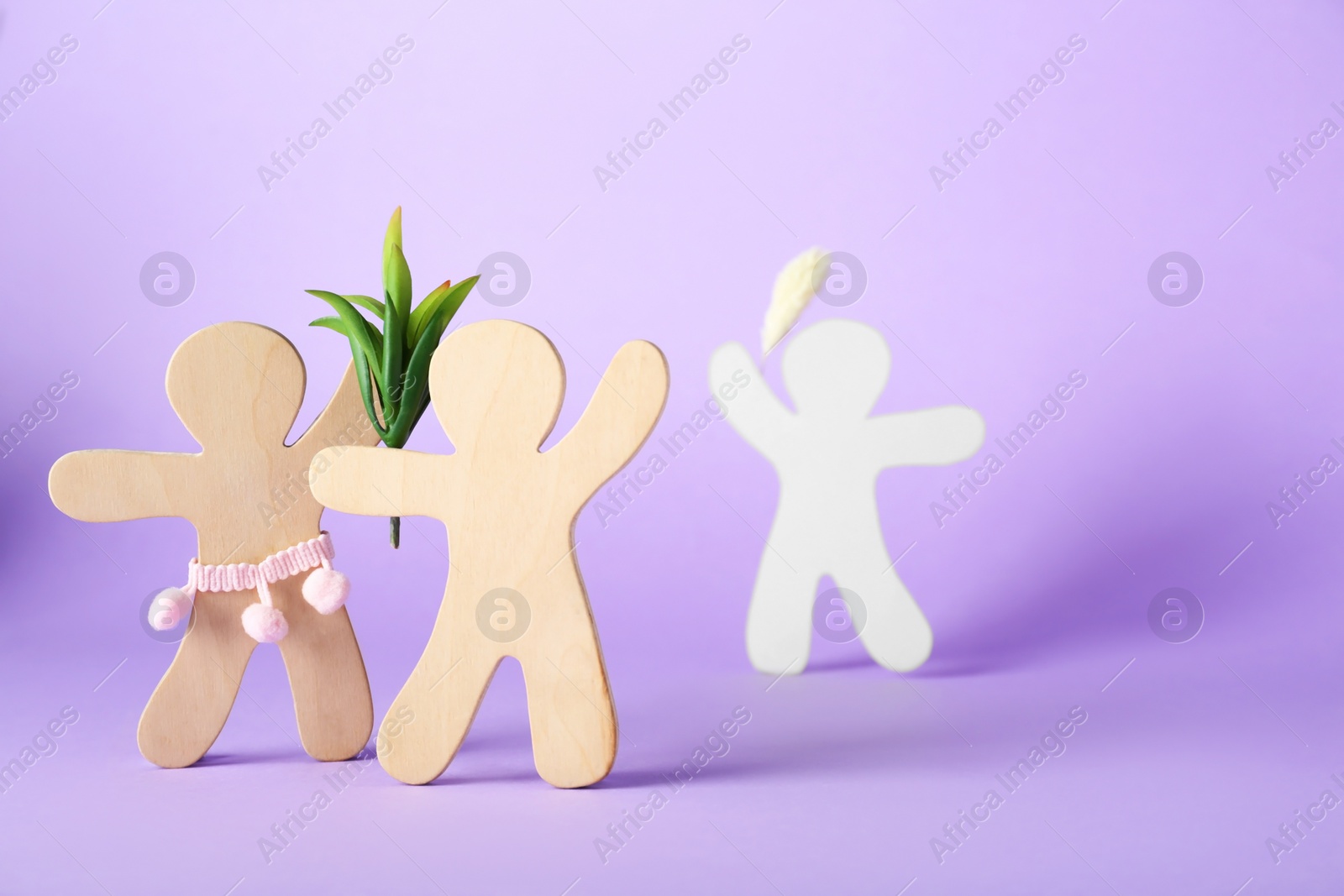 Photo of Wooden human figures fighting for attention of their beloved on lilac background, space for text. Jealousy concept