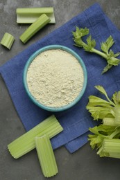 Photo of Natural celery powder in bowl and fresh stalks on grey table, flat lay
