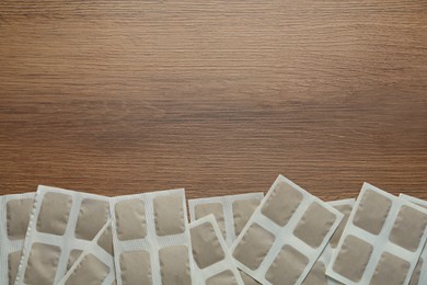 Photo of Mustard plasters on wooden table, flat lay. Space for text