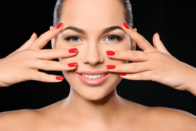 Photo of Beautiful young woman with bright manicure on black background, closeup. Nail polish trends