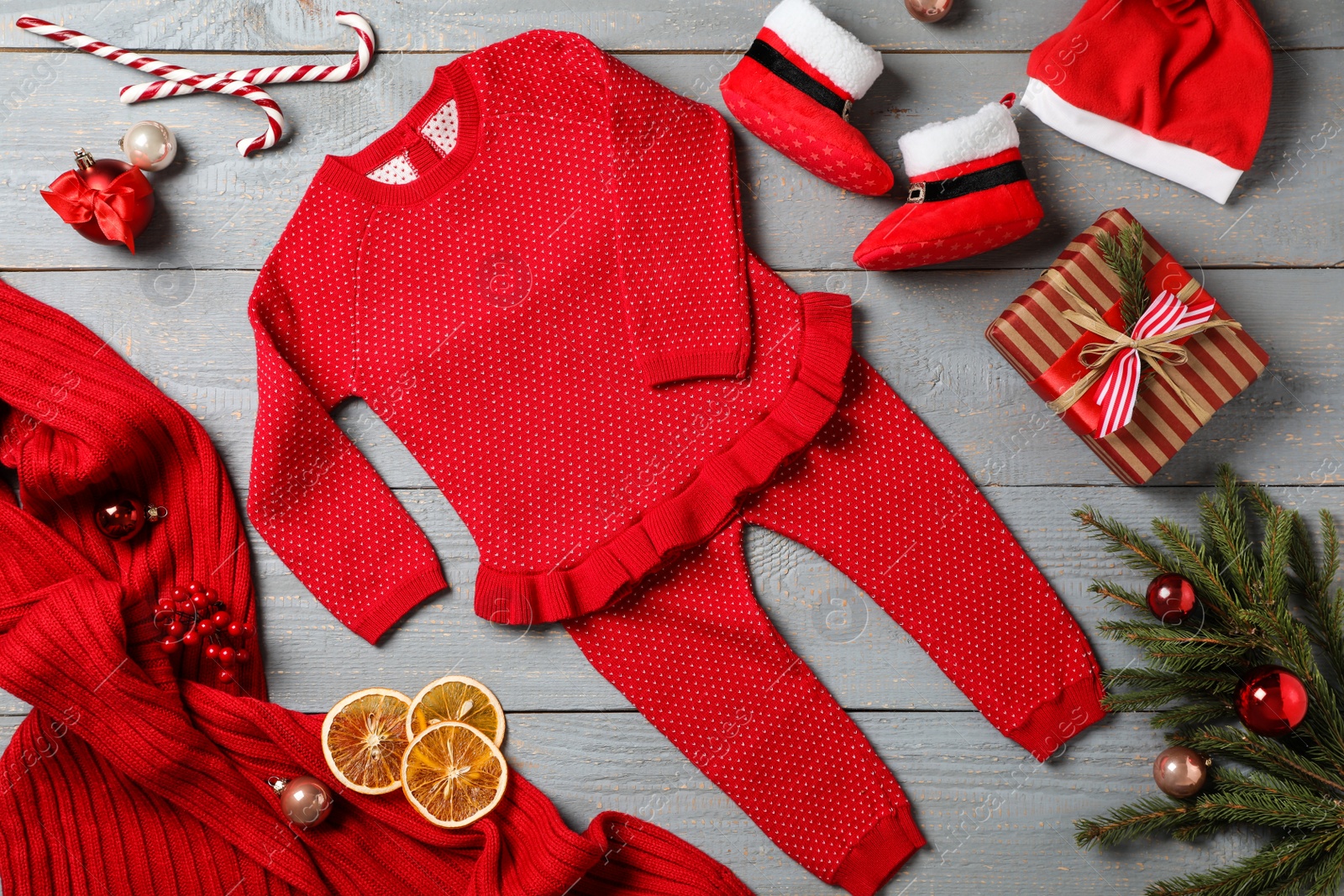 Photo of Flat lay composition with cute Christmas baby clothes on grey wooden background