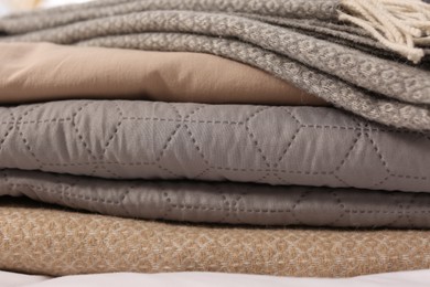 Photo of Stack of different folded blankets, closeup. Home textile