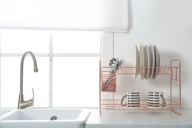 Photo of Clean dishes on drying rack in modern kitchen interior