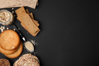 Photo of Rye crispbreads, rice cakes and rusks on black background, flat lay. Space for text