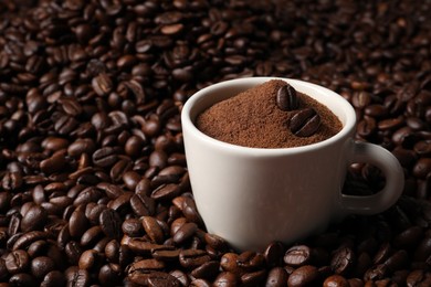 Photo of Cup with ground coffee on roasted beans. Space for text