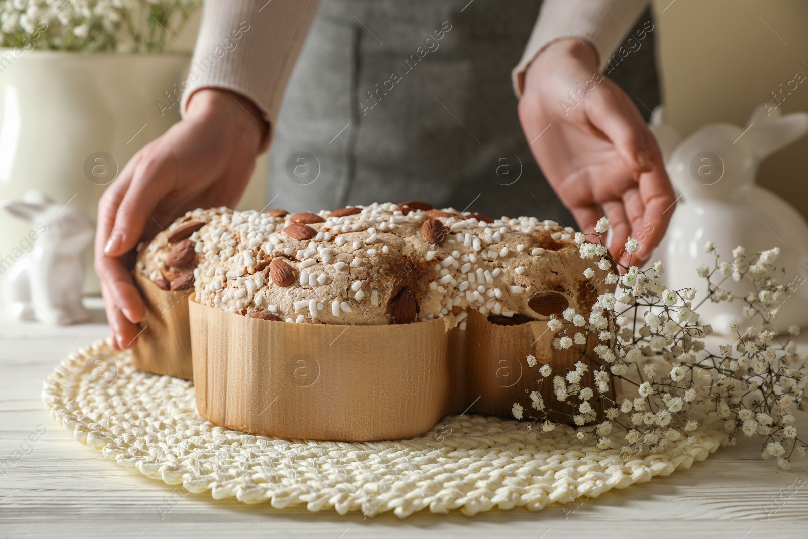 Photo of Woman taking delicious Italian Easter dove cake (traditional Colomba di Pasqua) at white wooden table, closeup