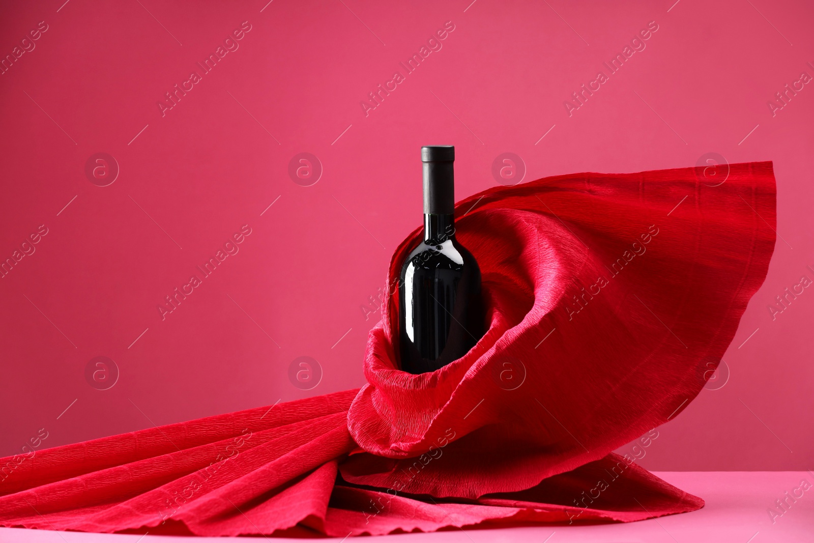 Photo of Stylish presentation of delicious red wine in bottle on pink background. Space for text