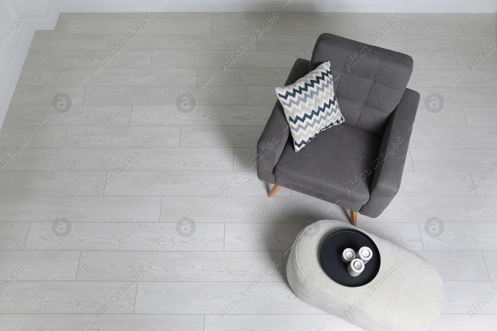 Photo of Stylish grey armchair and pouf with candles in room, above view. Interior design