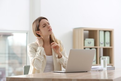 Photo of Woman suffering from neck pain in office. Symptom of bad posture