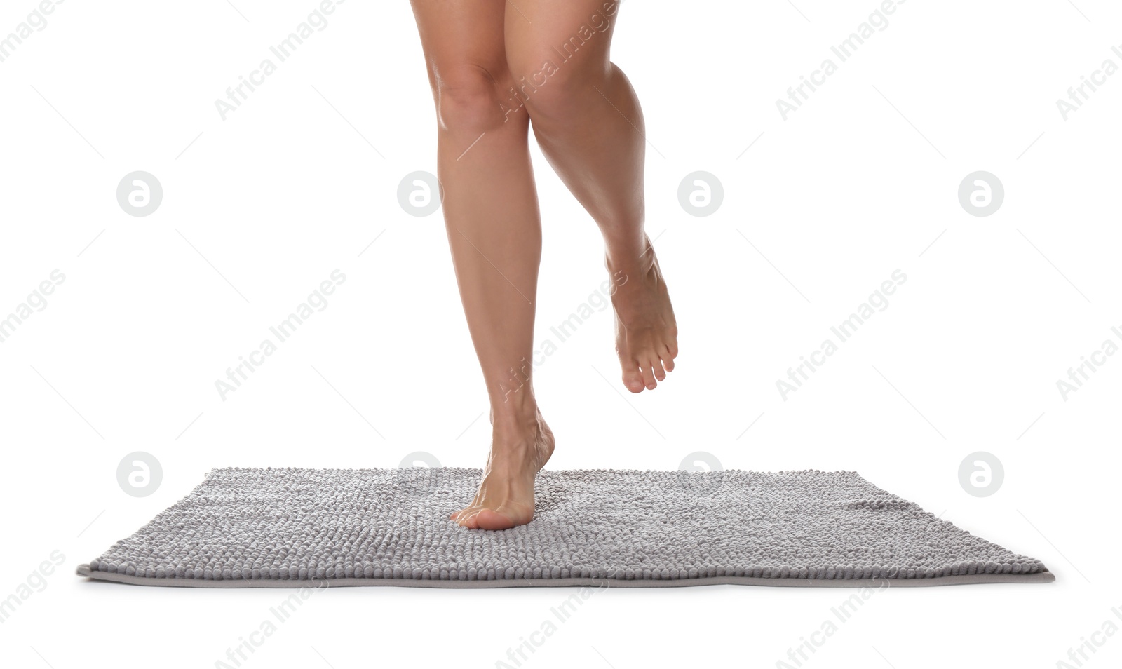 Photo of Woman standing on soft grey bath mat against white background, closeup